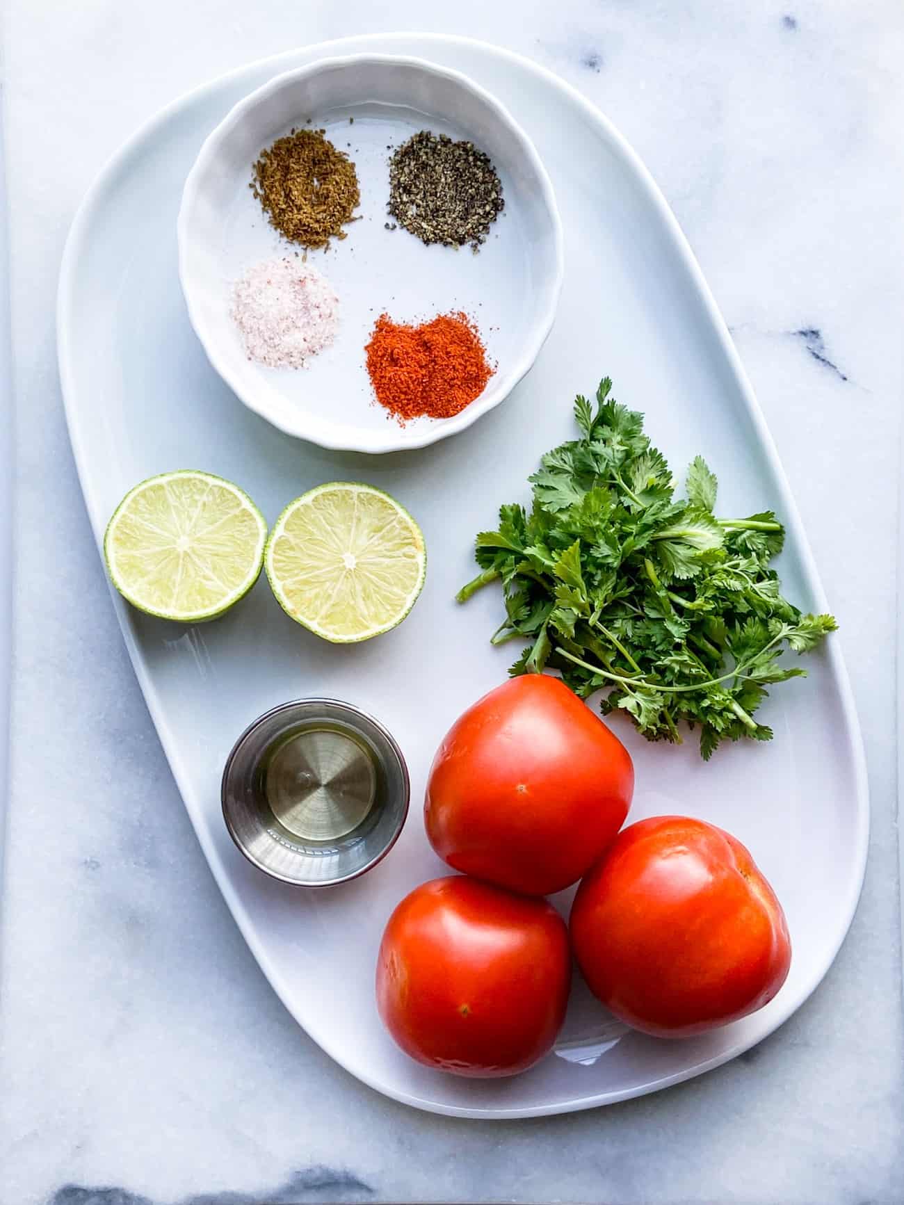 Red tomato, green lime and cilantro on a plate for Tomato salad.
