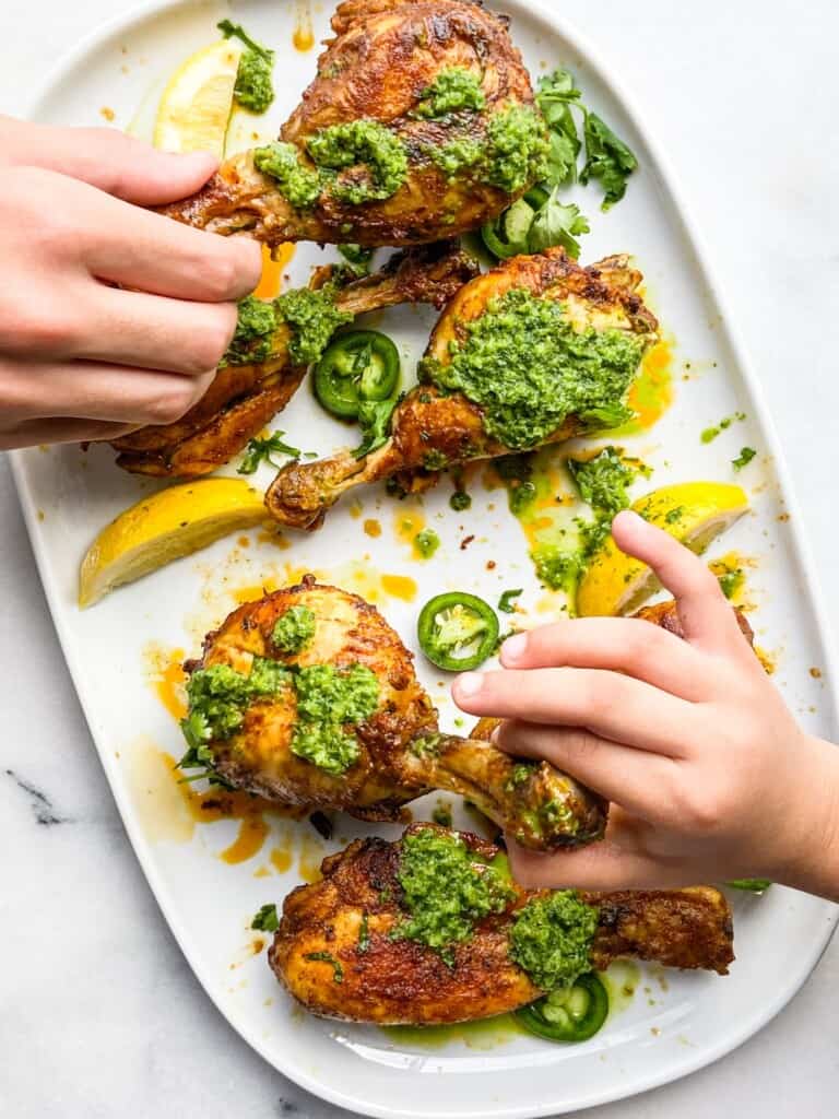 People holding oven roasted tandoori chicken