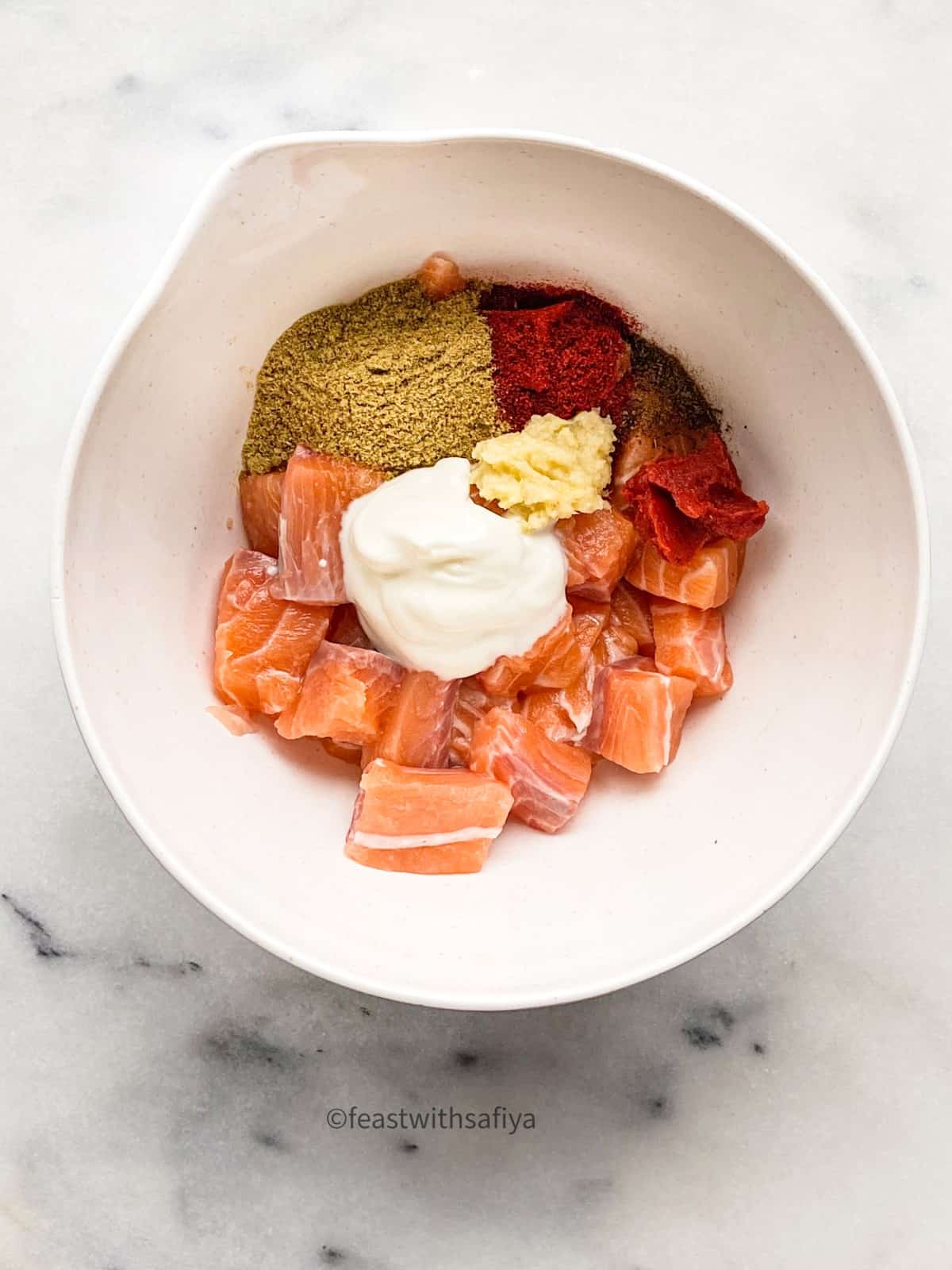 Salmon cubes and Indian spices in a white bowl