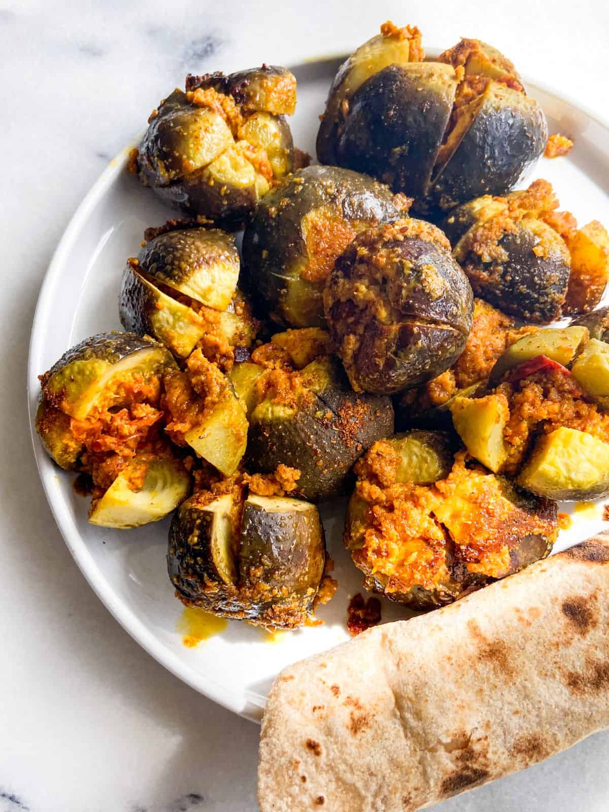 Cooked Indian stuffed baby eggplant with Indian flatbread roti on a plate