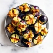 Uncooked stuffed baby eggplants (Bharwa Baingan) arranged on a white plate