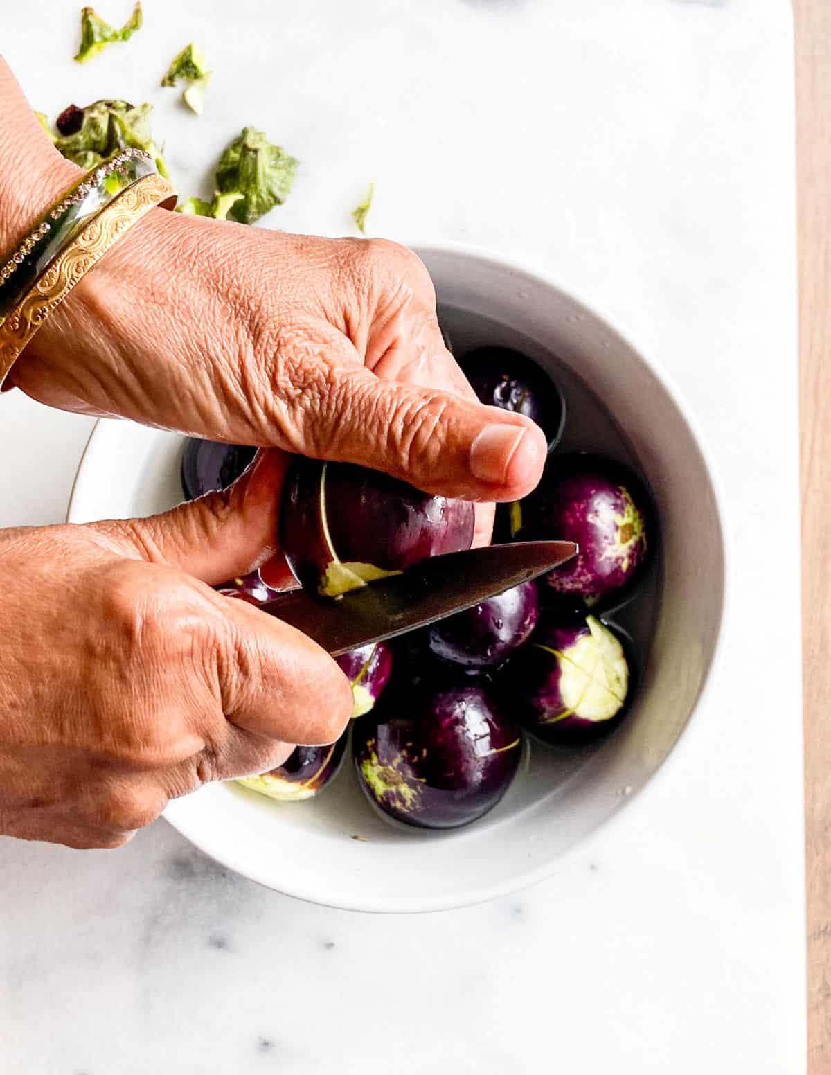 Slicing baby eggplants for stuffed eggplant aka brinjal recipe preparation