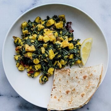 Palak paneer stir fry served with roti and lemon wedge