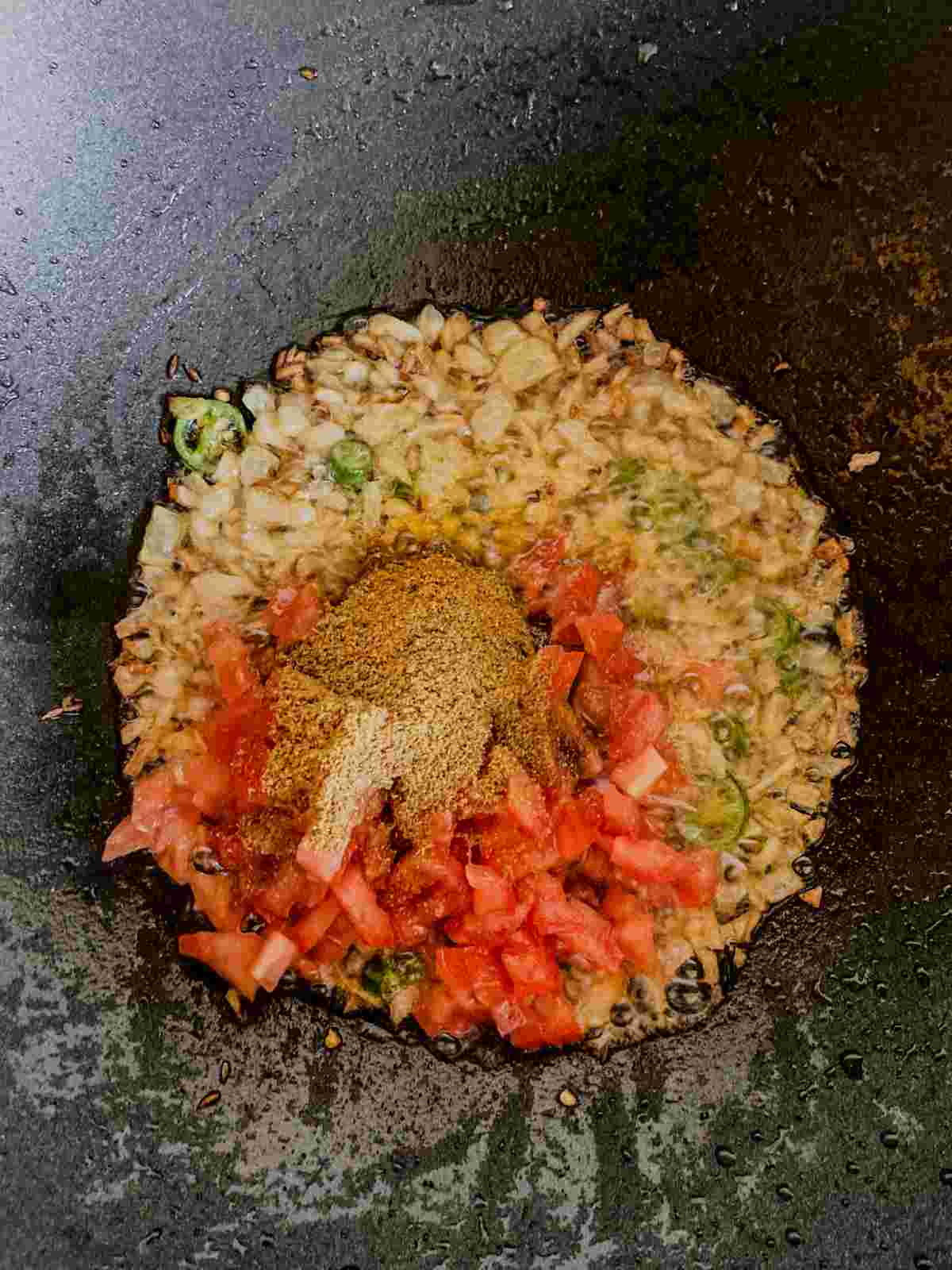 Chopped tomato and spices added to the onion mixture